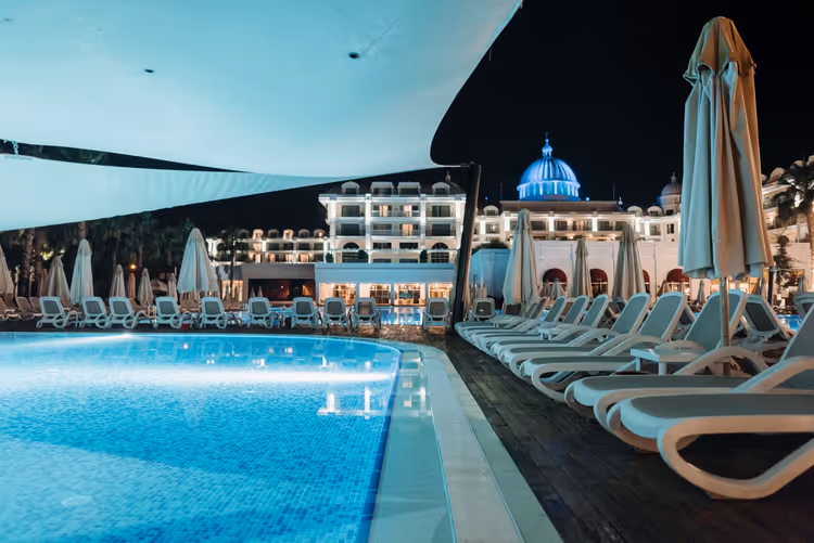 Geceleyin şezlonglu ve şemsiyeli otel havuzu