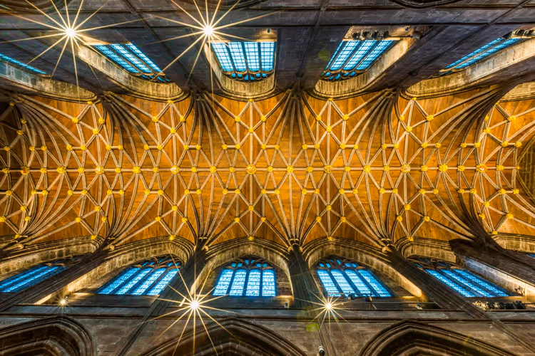 Goldenes gotisches Rippengewölbe von unten gesehen, eingerahmt von Reihen blau beleuchteter Bogenfenster