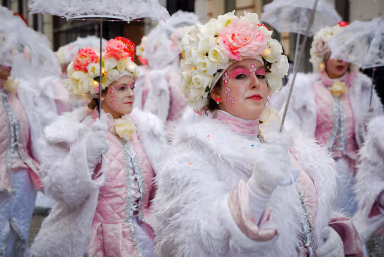 Karnevalsteilnehmer mit Blumenkränzen und Regenschirmen