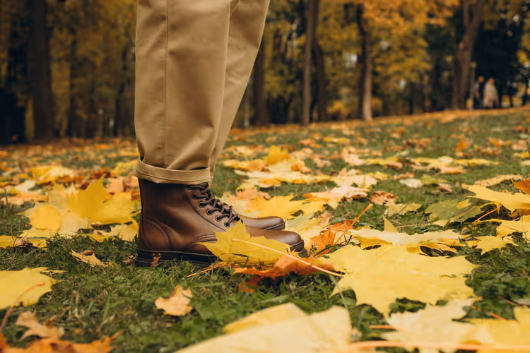 Bruine leren laarzen op herfstbladeren in een park