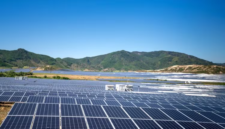 a large field of solar panels with mountains in the background