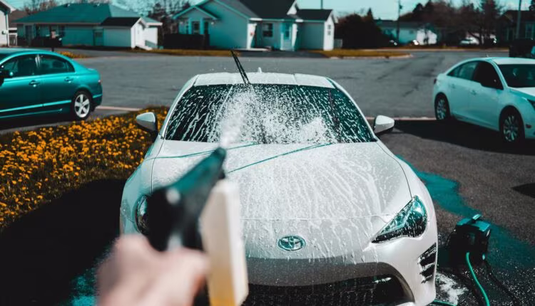 person spraying water on vehicle