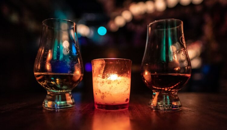 selective focus photography of two clear footed glasses placed near votive candle on table