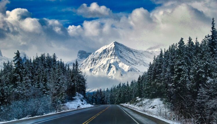 gray asphalt road near snow covered mountain during daytime