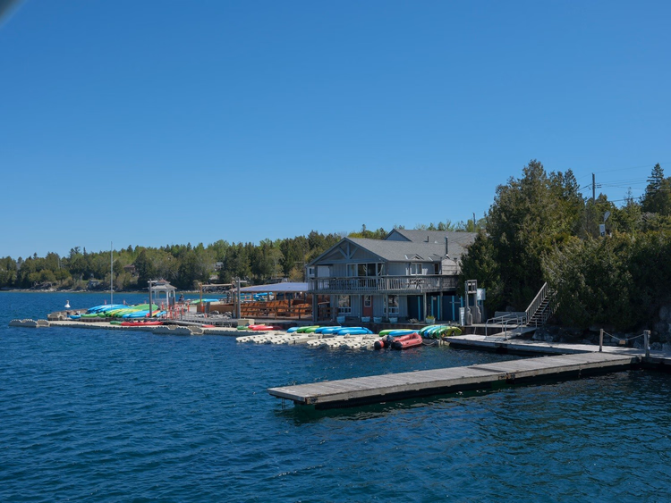 Ein Haus am Wasser und bunte Boote an einem Anleger