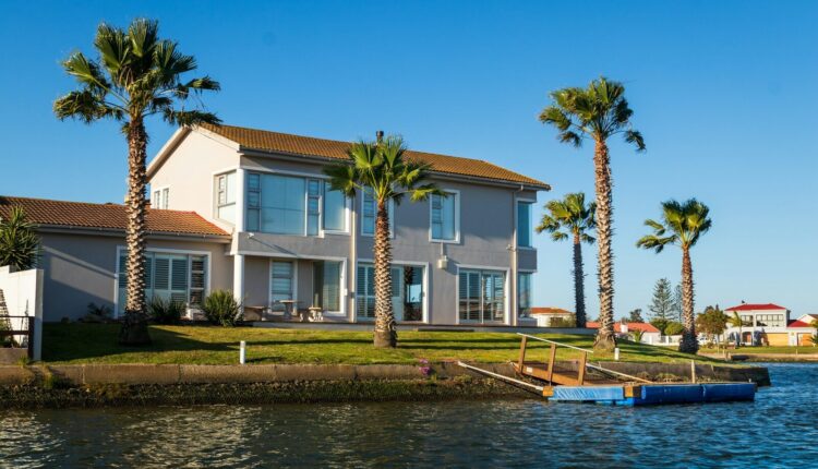 white and brown concrete house beside body of water during daytime